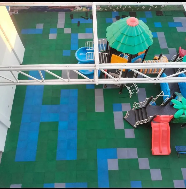 Overhead view of a rooftop playground on green, blue and gray rubber tile