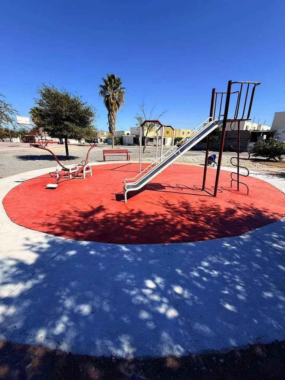 Playground equipment on red rubber flooring in a park