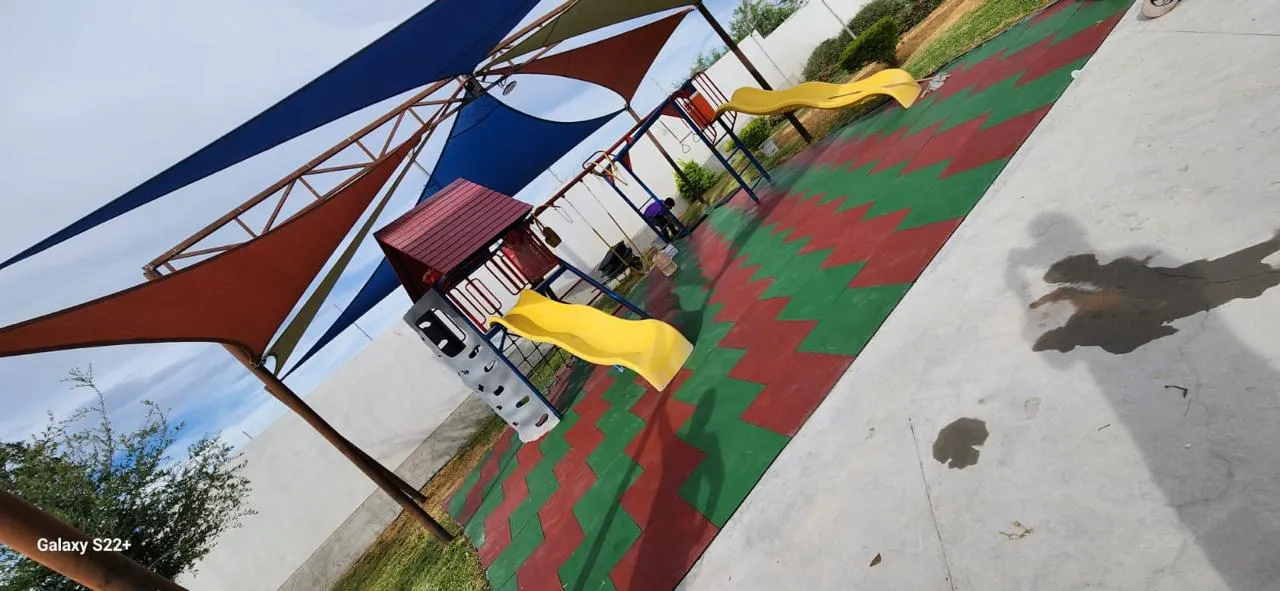 Children's play area under shade sails with red and green rubber tile
